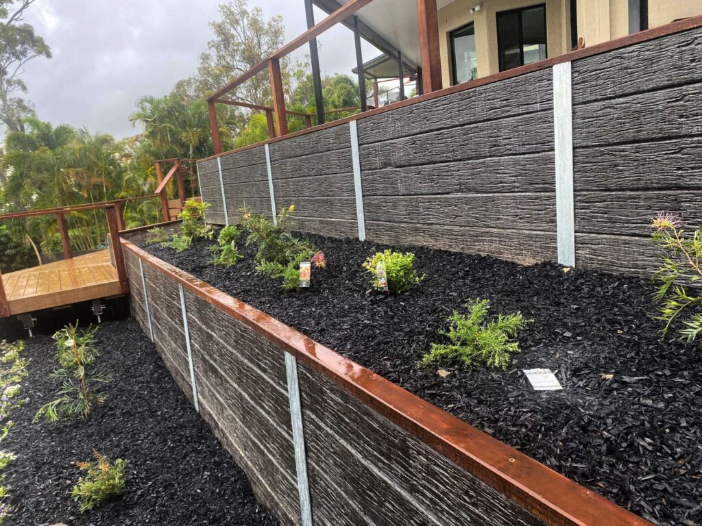 Retaining wall builder Gold Coast that built this tiered timber retaining wall with staircase and landscaped garden beds on a sloping property